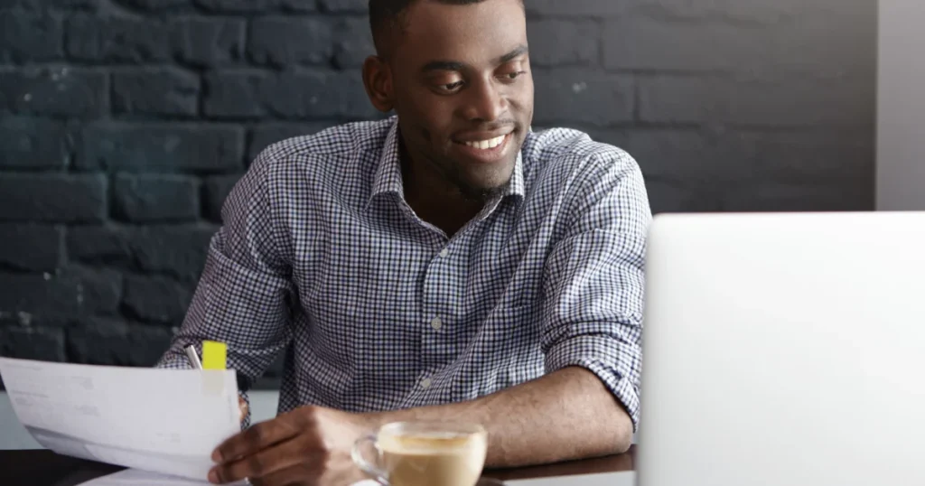 Young professional reviewing documents while completing a personal loan application on a laptop